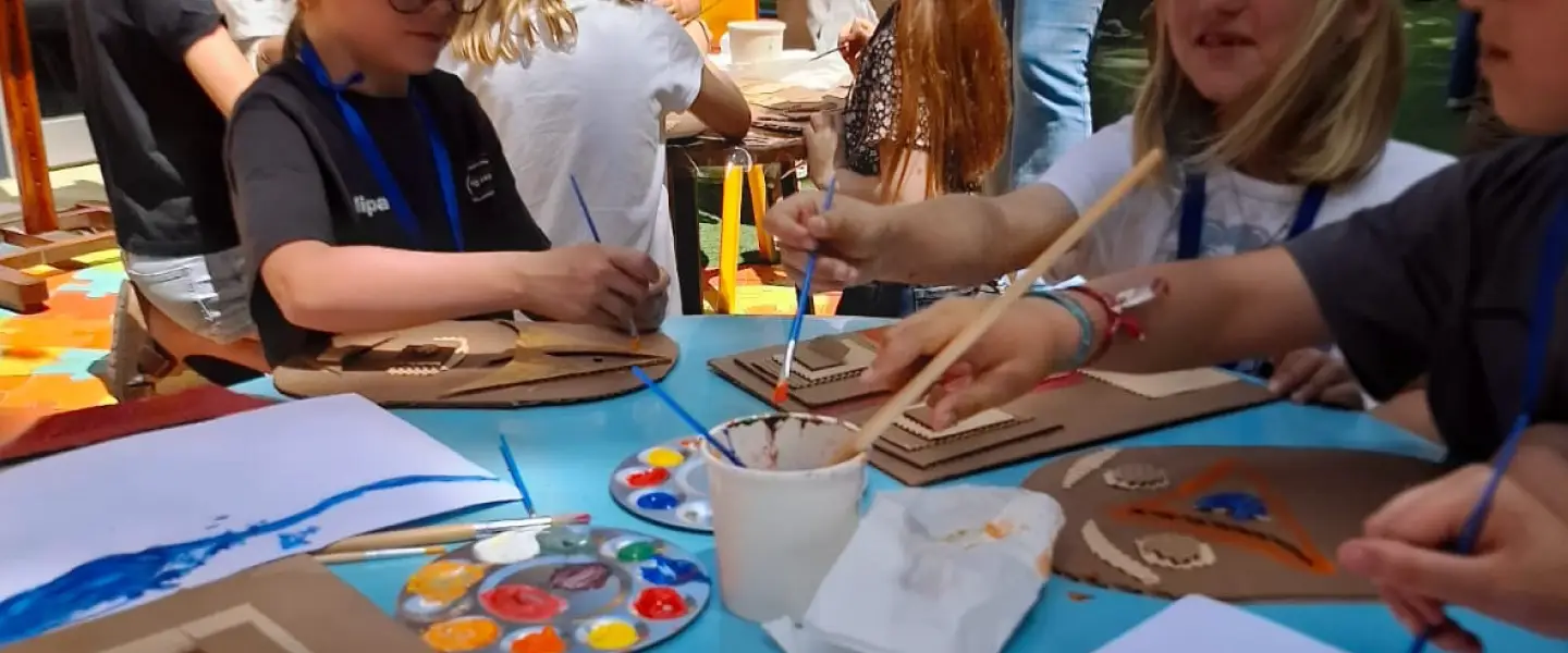 Niño pintando una obra de cartón durante una actividad artística